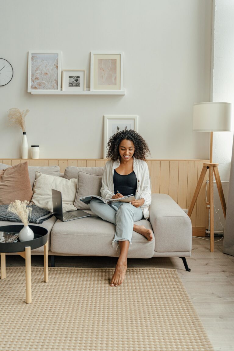 black woman in casual cothes working with laptop in a neutral coloured room